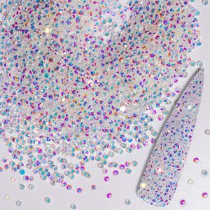 Iridescent rhinestones scattered, glimmering on a reflective surface, with some affixed to a long, pointed fingernail tip at the side.