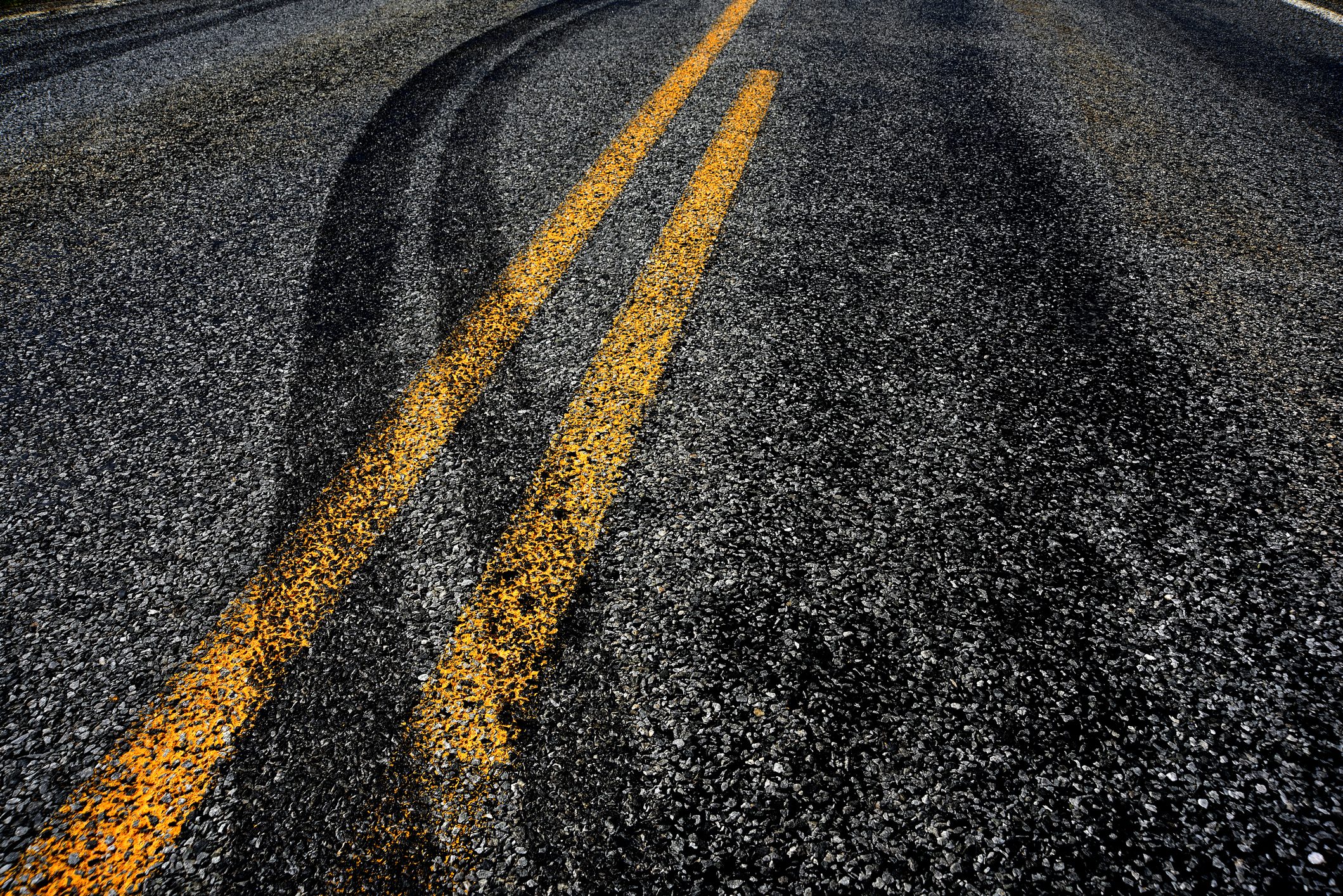 skid marks crossing the double yellow line on a road, evidence of a car accident