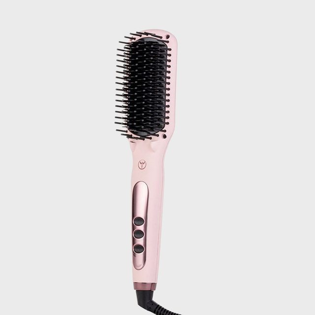 A pink electric hairbrush with black bristles sits idle, featuring three buttons on its handle against a plain light grey background.