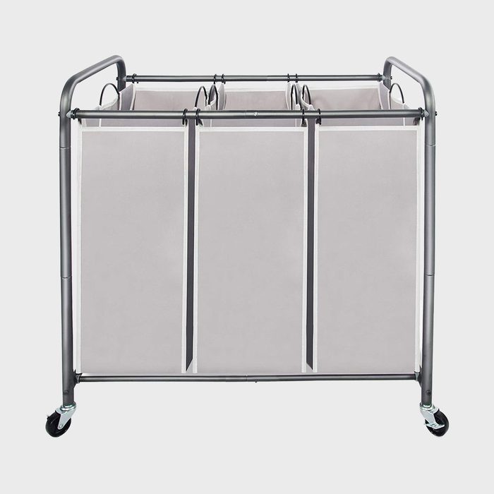 A rolling laundry sorter with three compartments stands on a gray floor, featuring a metal frame and caster wheels.