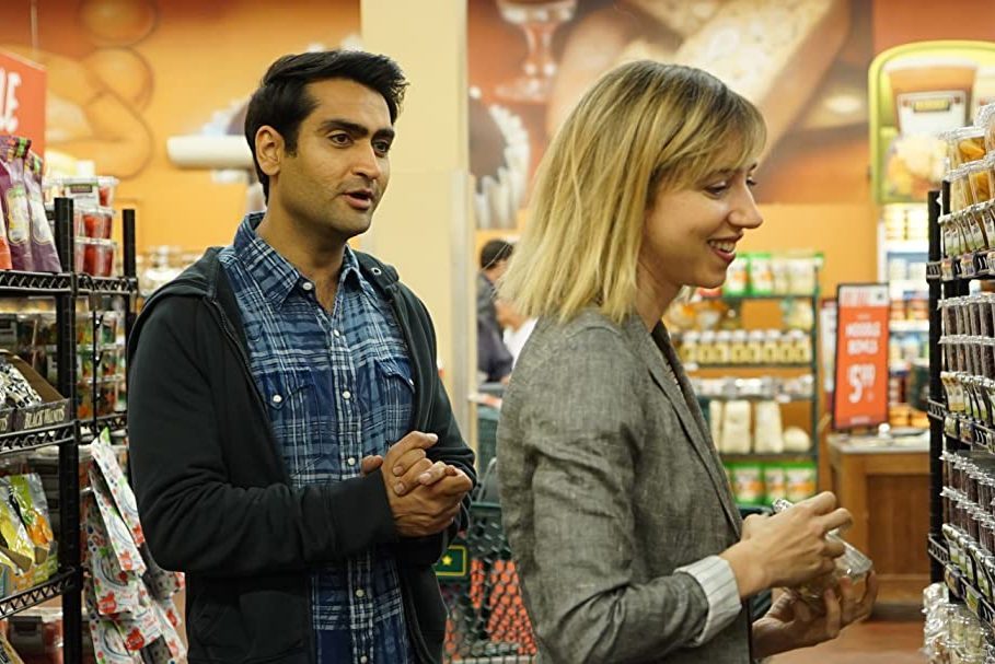 Two people converse while grocery shopping, surrounded by shelves filled with various packaged foods in a supermarket.