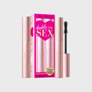 Mascara tubes stand upright beside a pink and white package with bold text, 