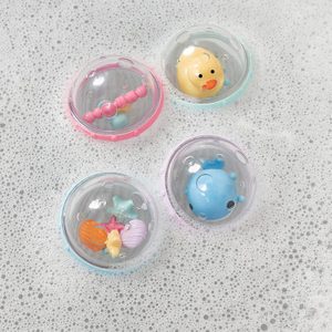 Plastic balls float, containing colorful toys, amidst soapy water.