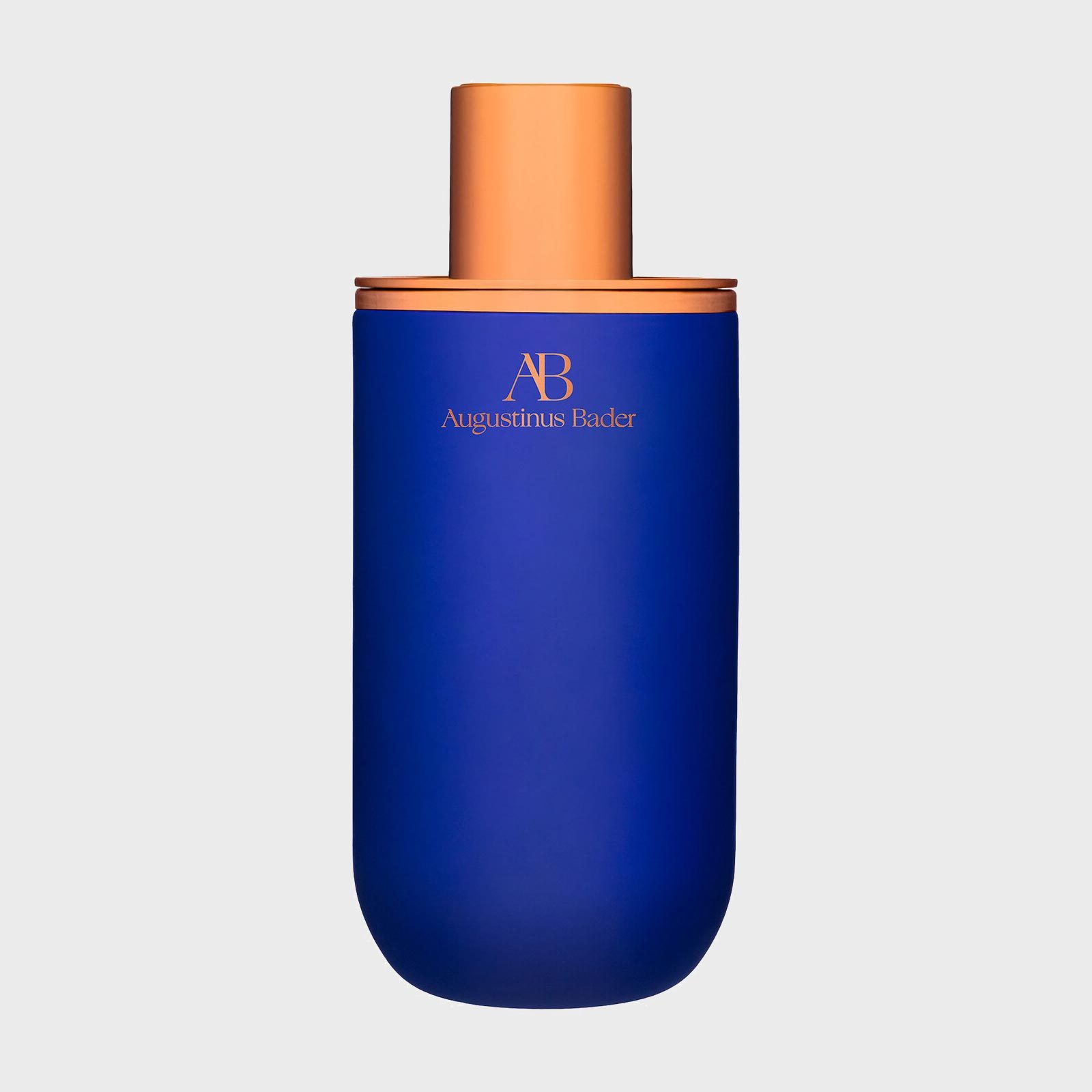 A blue bottle with a gold cap, labeled "Augustinus Bader," stands against a plain, light gray background.