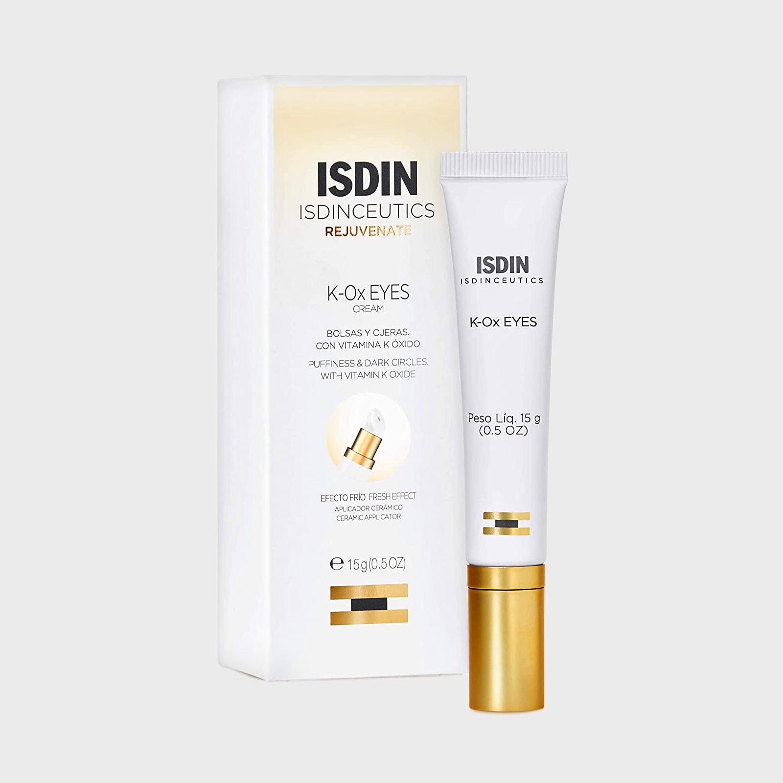 Tube stands beside box packaging cream for puffiness around eyes, featuring vitamin K oxide. White and gold theme, text details product benefits.