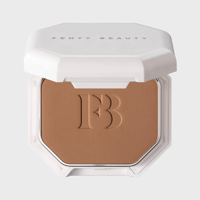 Compact powder is open, displaying embossed initials, with 