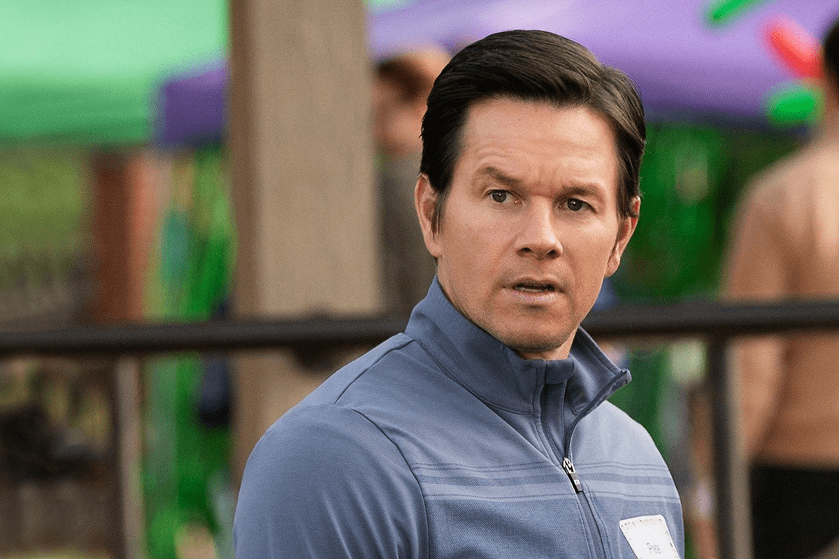 Man wearing blue jacket looks alert outdoors, with colorful blurred background.