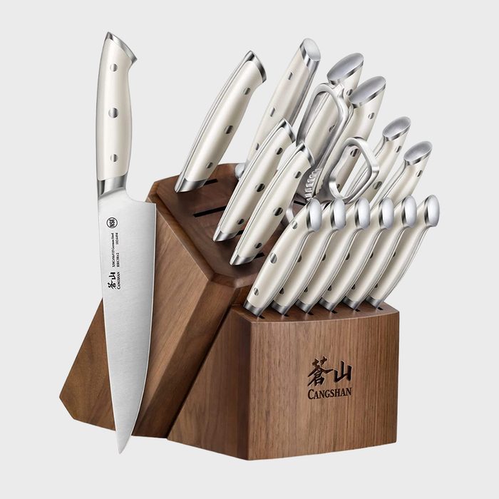 Knife set resting in a wooden block, displaying sleek silver handles; photographed against a plain, light background, labeled 
