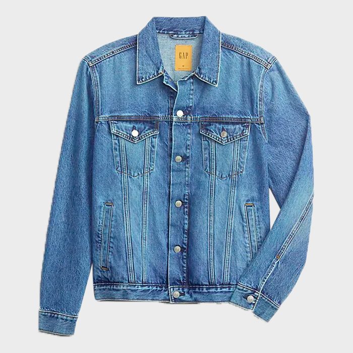Denim jacket lying flat, featuring button-up front and pockets, set against a plain white background. 