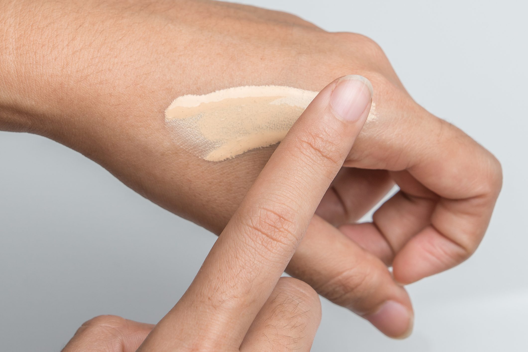Copped Hand Applying Foundation On Hand Over White Background