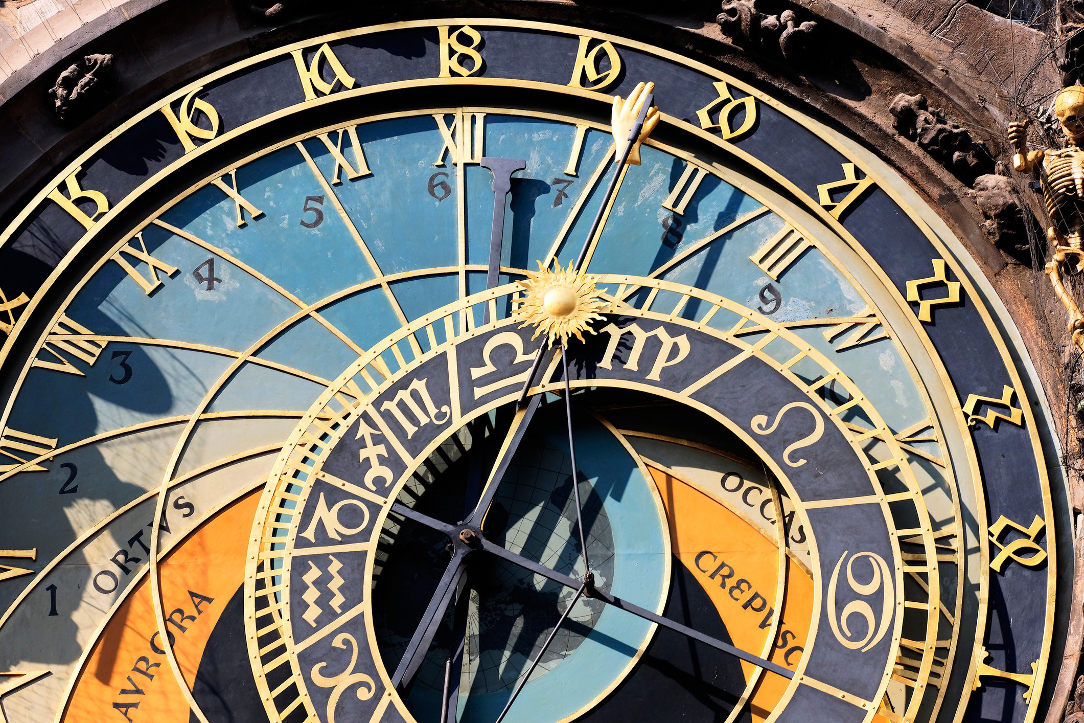 Astronomical clock with intricate gold numerals and zodiac symbols, displaying time, surrounded by detailed medieval decorations on a historic building.