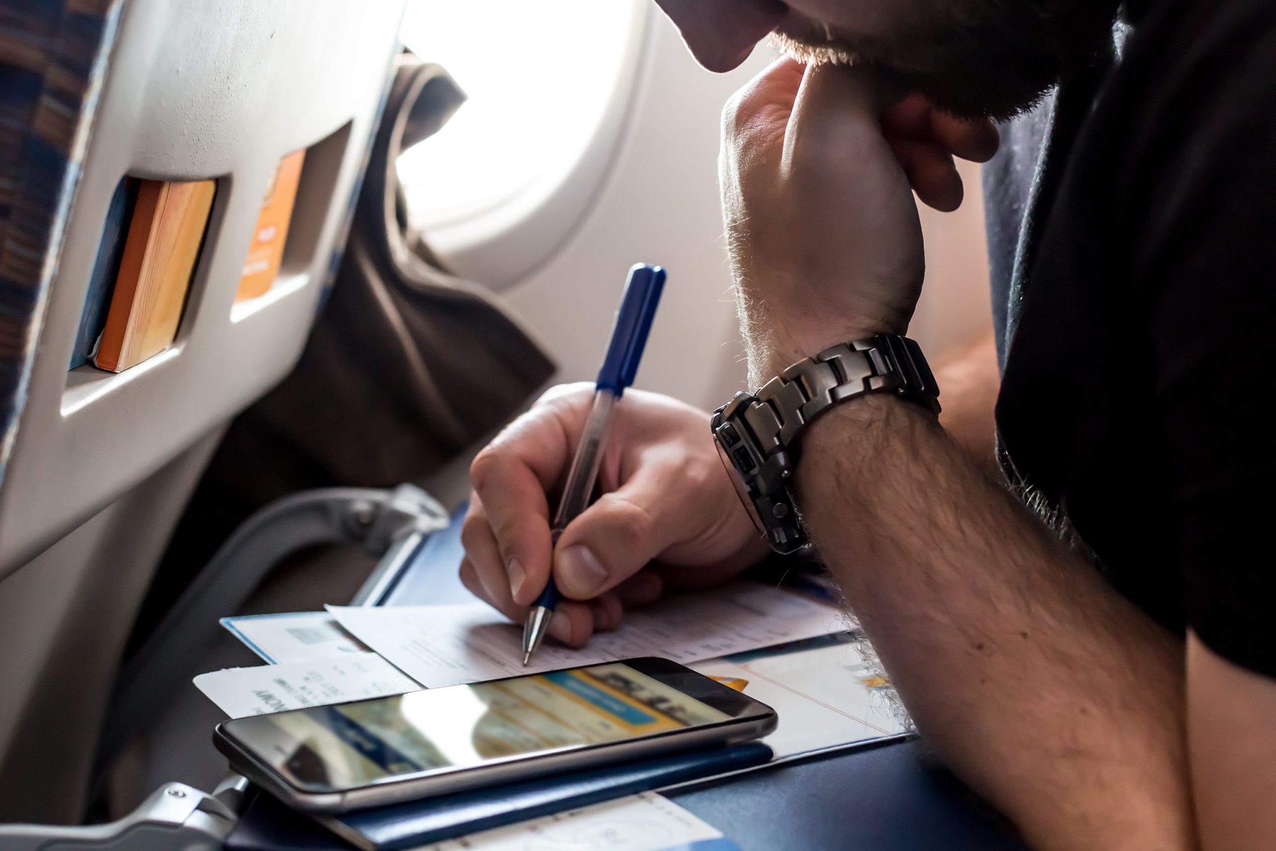 Bearded pensive Man filling Immigration Form in Aircraft