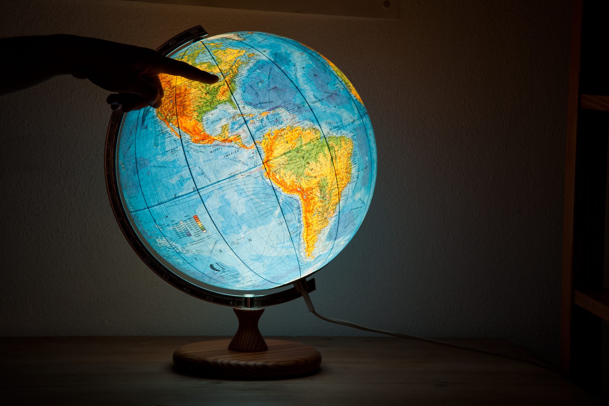 A lit globe is pointed at, illuminating a dark room with wooden surfaces.