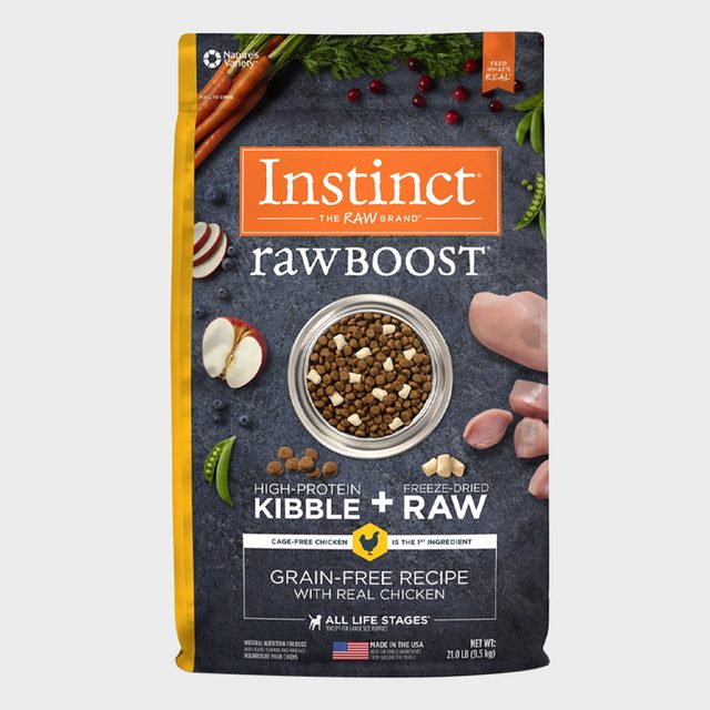 Dog food package displays high-protein kibble with freeze-dried raw in a bowl; surrounded by carrots, apple slices, and chicken pieces.