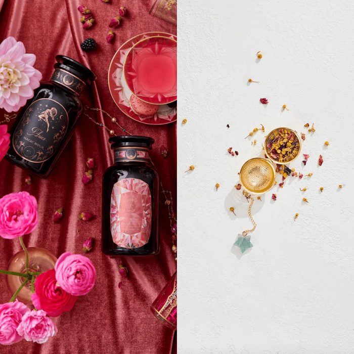 Bottles rest on a velvet fabric amidst flowers and macarons; a tea infuser holds herbs on a white textured surface.