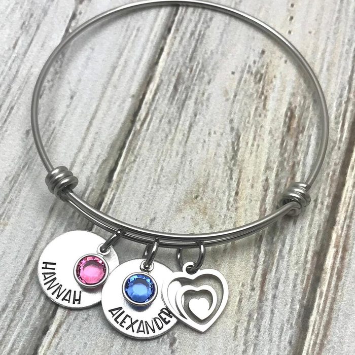 Bracelet displays three charms: pink, blue gems with names 