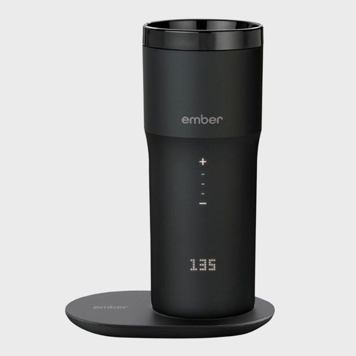 A black smart mug on a charging coaster displays 
