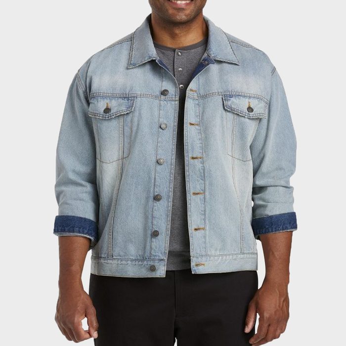 Denim jacket worn by a person, sleeves rolled up, over a grey shirt against a plain background.