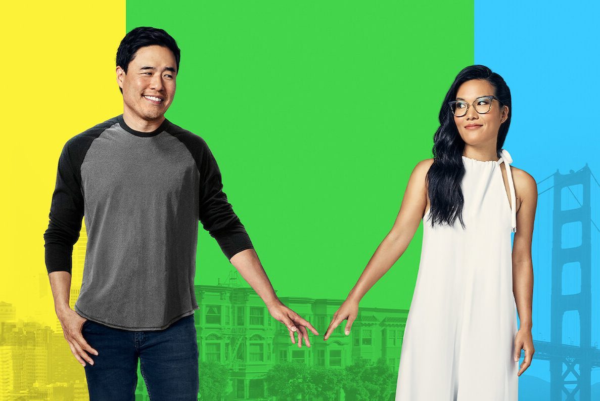 Two people touch fingertips, smiling, against a colorful background with cityscape and bridge silhouette.