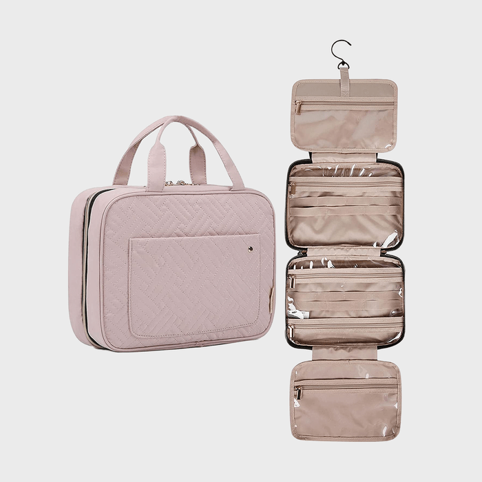 Quilted pink travel bag, hanging open with multiple zippered compartments, displayed against a plain background.