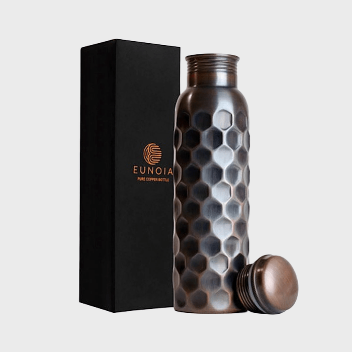 Copper bottle with hexagonal pattern stands beside a black box labeled 