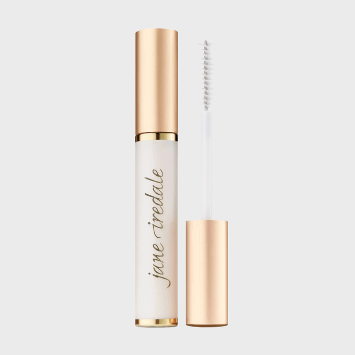 Mascara with a gold cap stands open, displaying a white brush. Text reads 