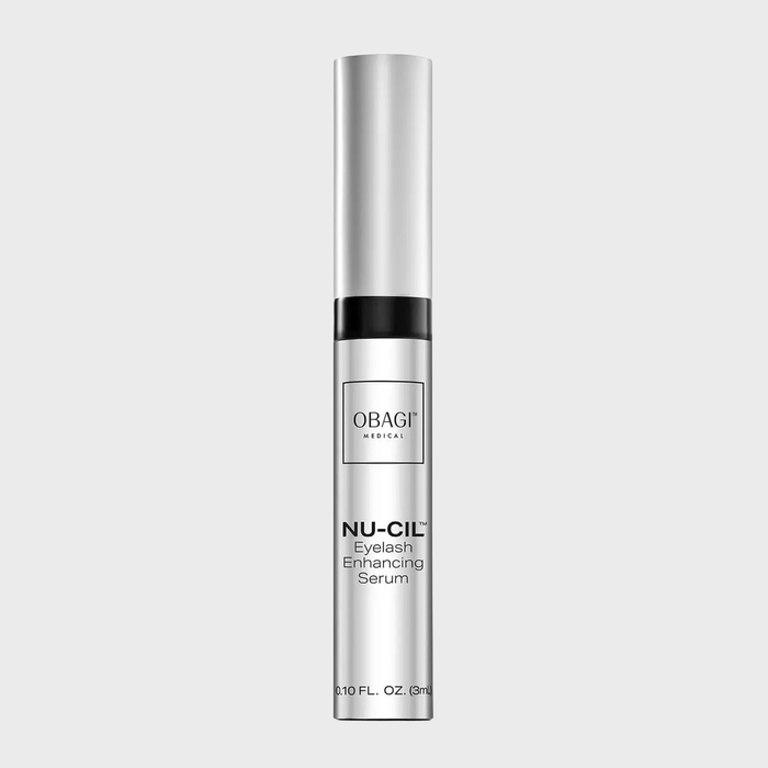 A silver tube of Obagi Nu-Cil Eyelash Enhancing Serum stands upright against a plain background.