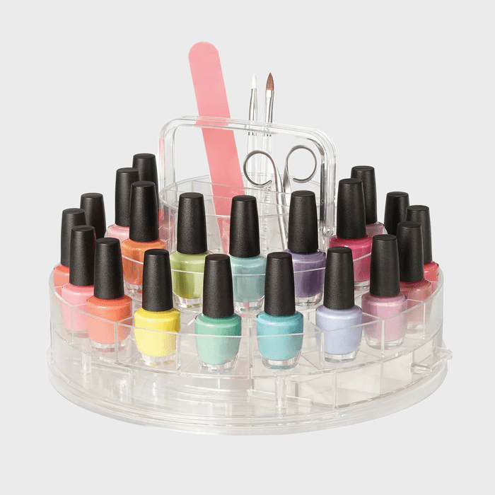 Nail polish bottles stand in a circular holder with multiple colors. Nail tools, including files and scissors, are set behind them.