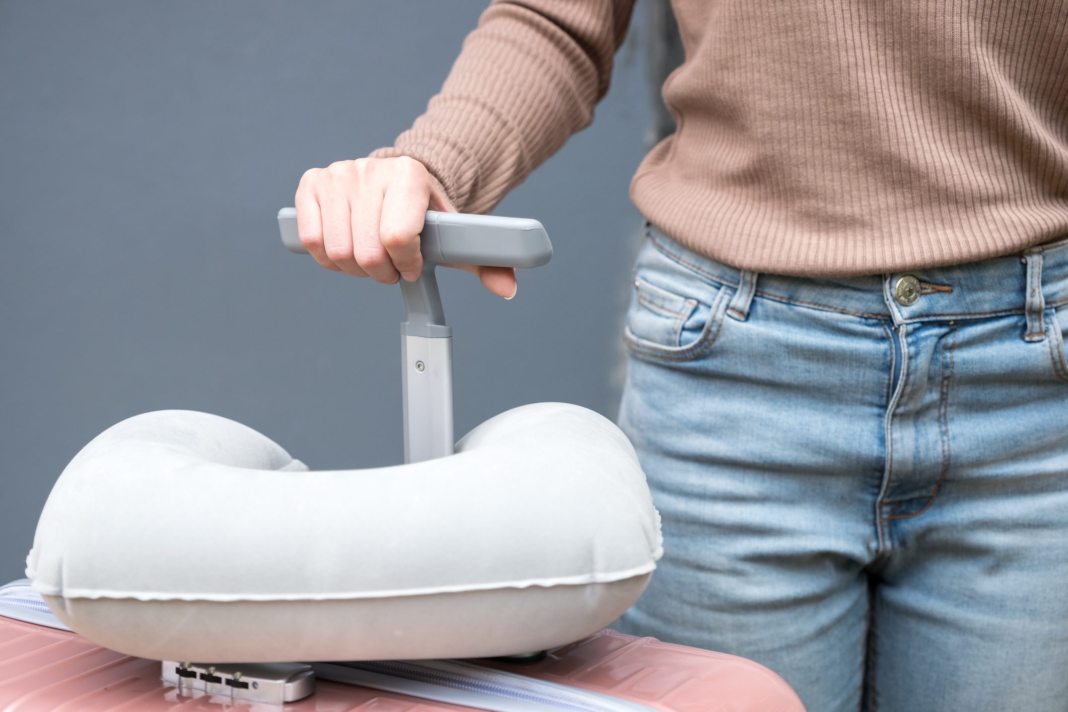 Midsection Of Woman Holding Suitcase With Neck Pillow