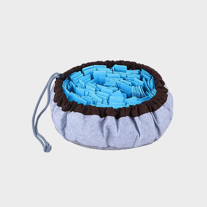 Drawstring fabric pouch holds folded blue cloth pieces, arranged densely, on a neutral background.