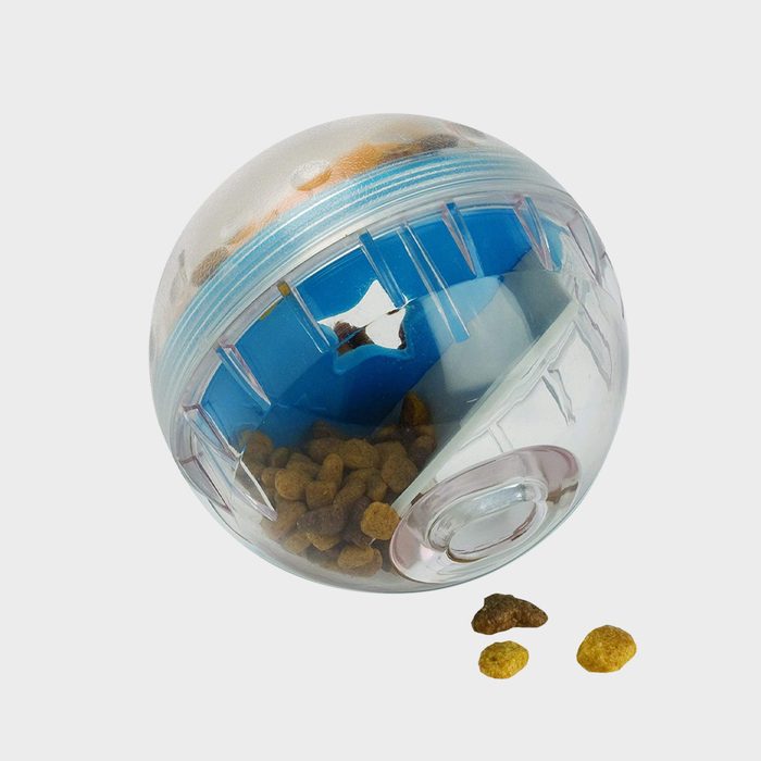 Clear plastic ball dispenses brown kibble, resting on a white surface.