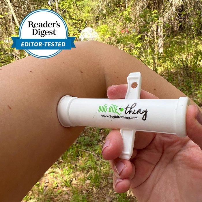 Device suctioning skin, reducing insect bites; held outdoors on an arm, surrounded by green foliage. Text: 