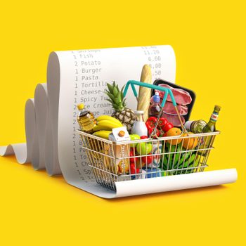 A shopping basket holds groceries, including bread, fruits, and meats, placed on a large printed receipt, against a bright yellow background.