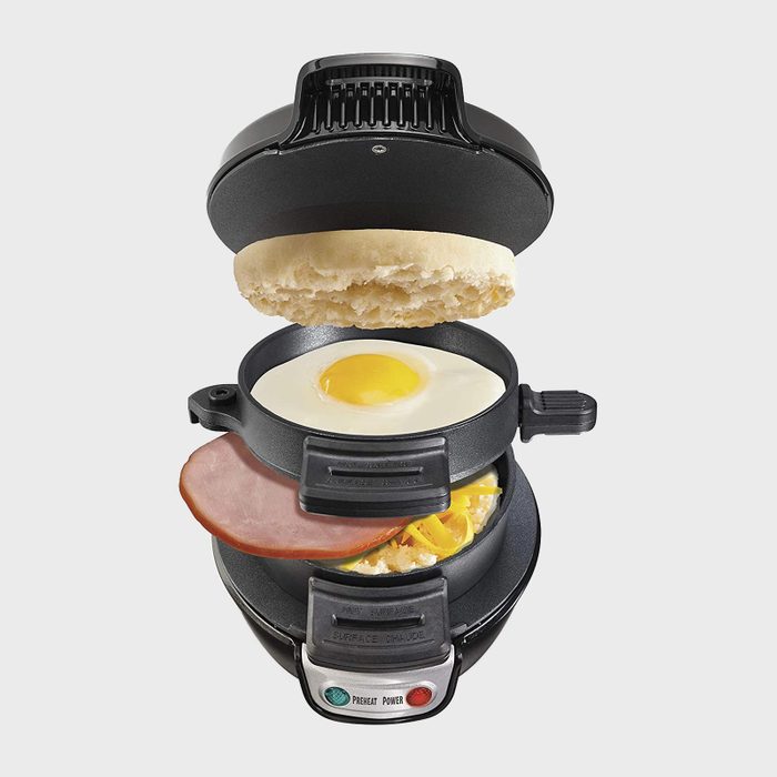 Sandwich maker assembling breakfast sandwich with egg, ham, and cheese in layered compartments; text reads 