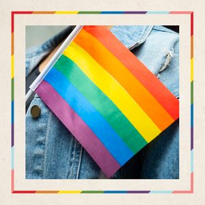 A rainbow flag rests on a denim jacket, framed by a colorful border, symbolizing diversity and inclusion.