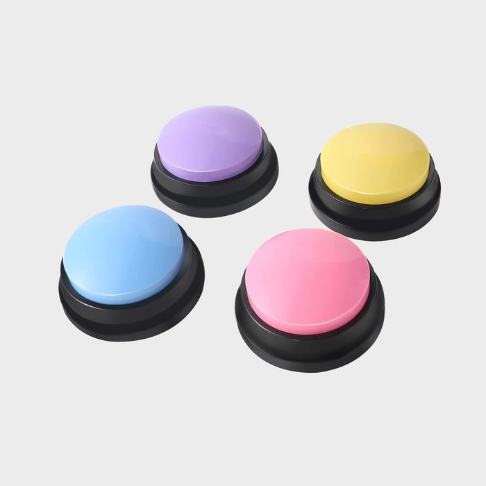 Four brightly colored buttons sit idle on a plain white surface, arranged in a square formation: blue, pink, yellow, and purple.