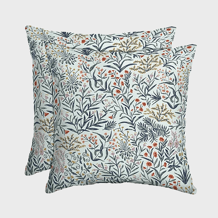 Two square pillows displaying a floral pattern are arranged overlapping, set against a plain white background.
