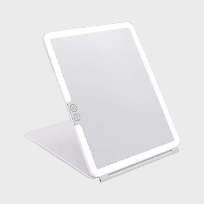 A white, rectangular mirror with adjustable stand and touch controls, set against a plain gray background.