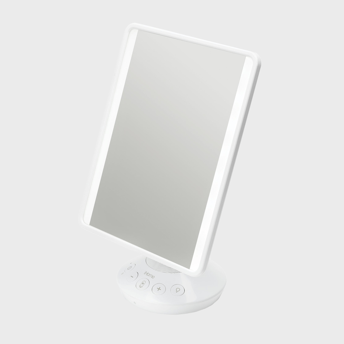Rectangular illuminated mirror tilts sideways, mounted on a white circular base with control buttons, against a plain gray background.