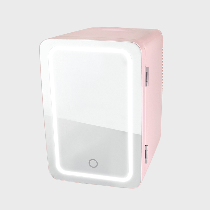Mini fridge stands idle, featuring a pink exterior and mirrored door, with a circular button at the bottom, set against a plain background.
