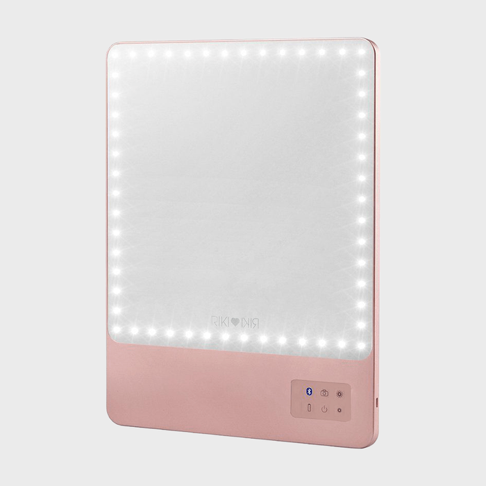 A rectangular mirror with perimeter LED lights, mounted in a pink frame, features touch controls on the lower right corner.