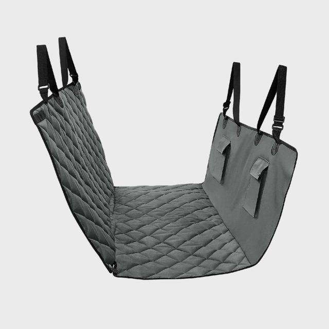 Quilted pet seat cover suspended with straps, positioned for use in a car, displaying a gray padded surface and storage pockets.