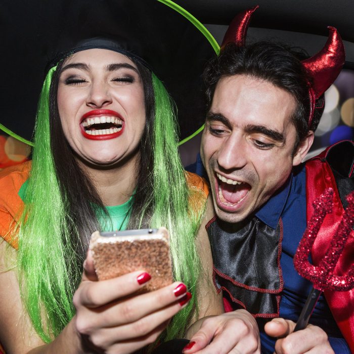Halloween witch and devil laughing in back of car