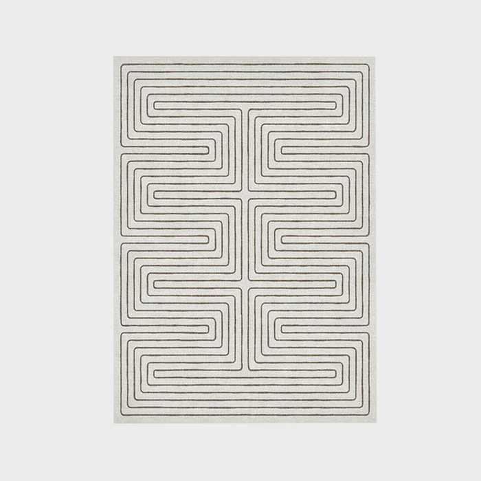 Rectangular rug displays a geometric pattern with brown concentric lines on a light background, creating a maze-like design.