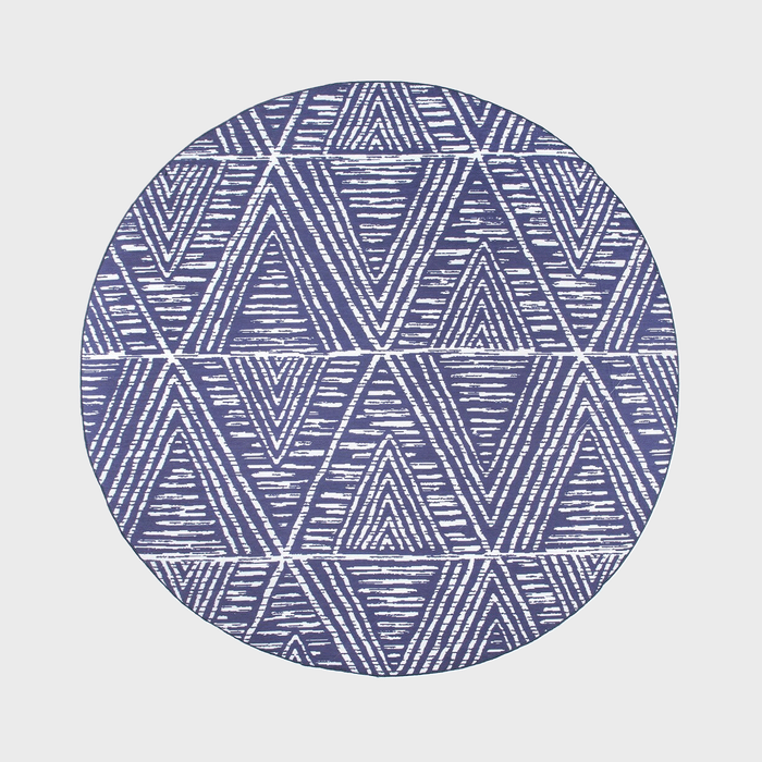 Round rug displays intricate blue and white geometric pattern featuring overlapping triangles, creating a textured appearance against a plain background.