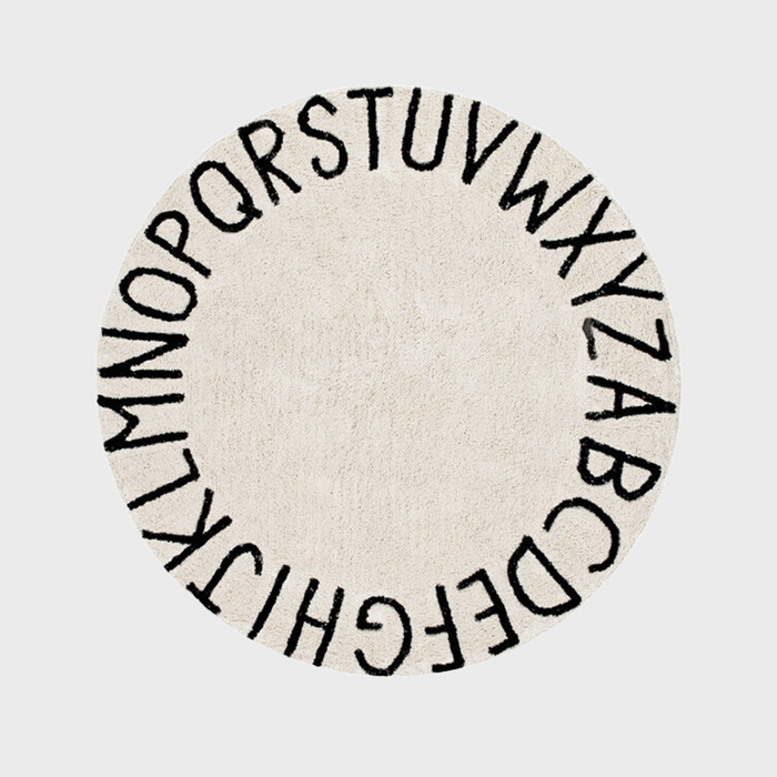 Round beige rug displays black alphabet letters in a circular arrangement on a plain gray background.