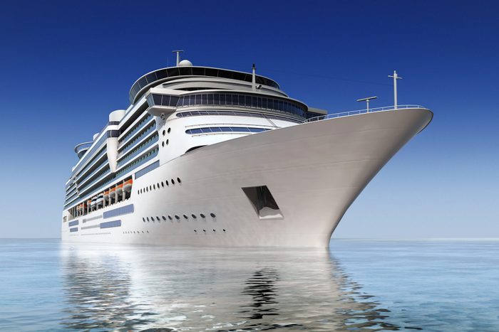 luxury white cruise ship shot at angle at water level on a clear day.