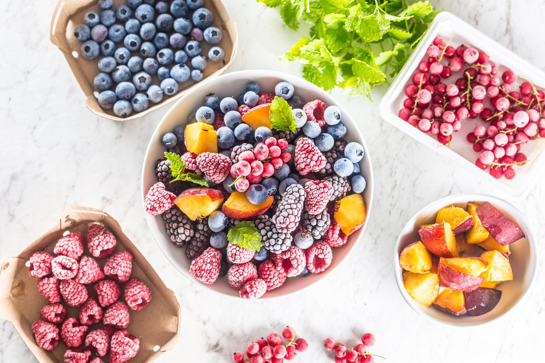 Frozen fruits and berries in various sized bowls on a kitchen counter