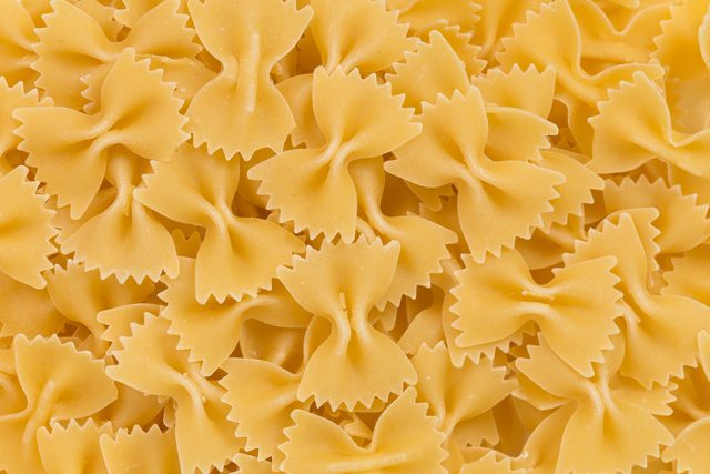 Bowtie pasta stacked, showing smooth, undulated shape in a closely packed arrangement.