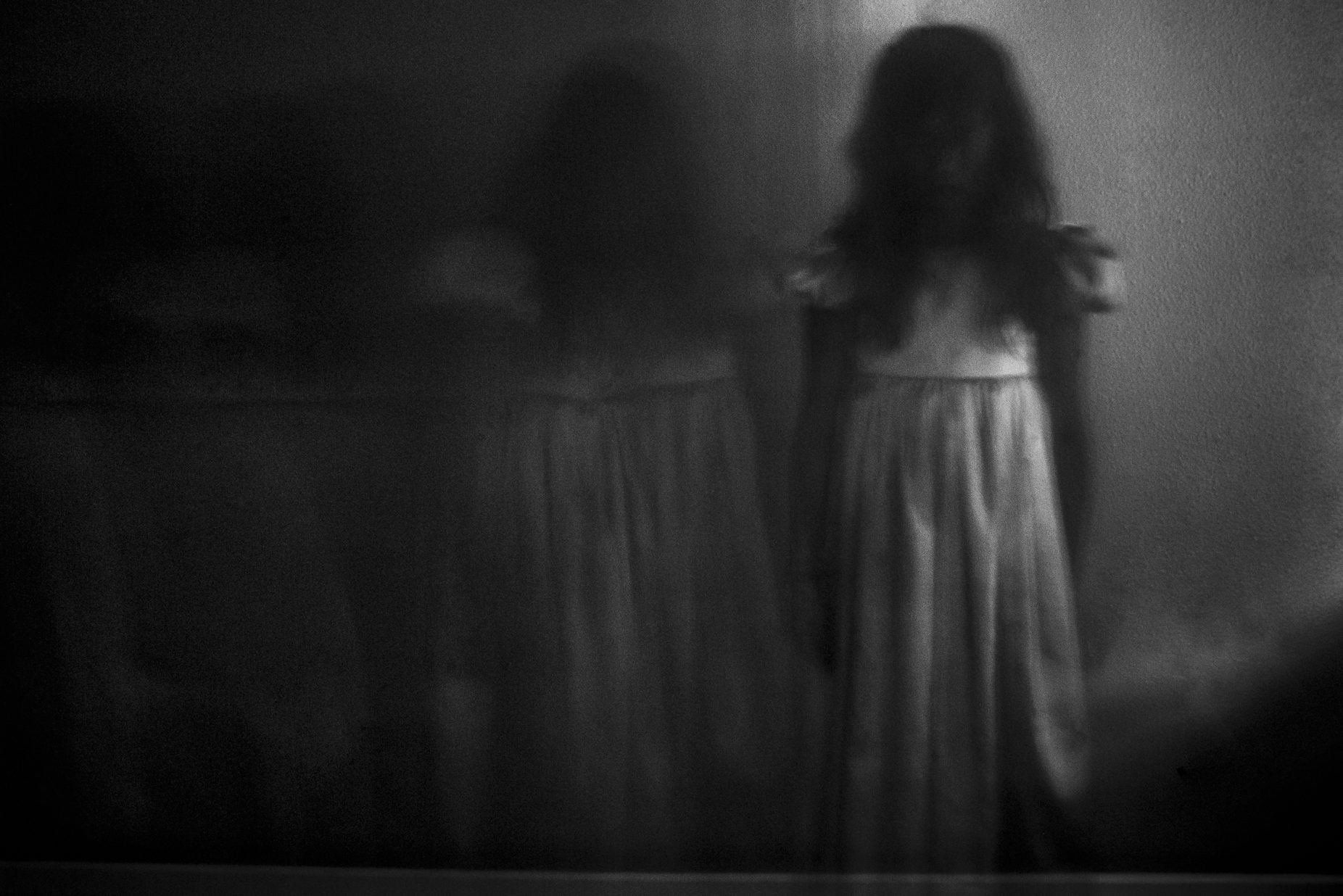 Double exposure of spooky girl against wall at home